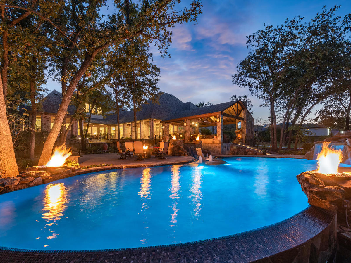 backyard pool surrounded by fire pits and patio